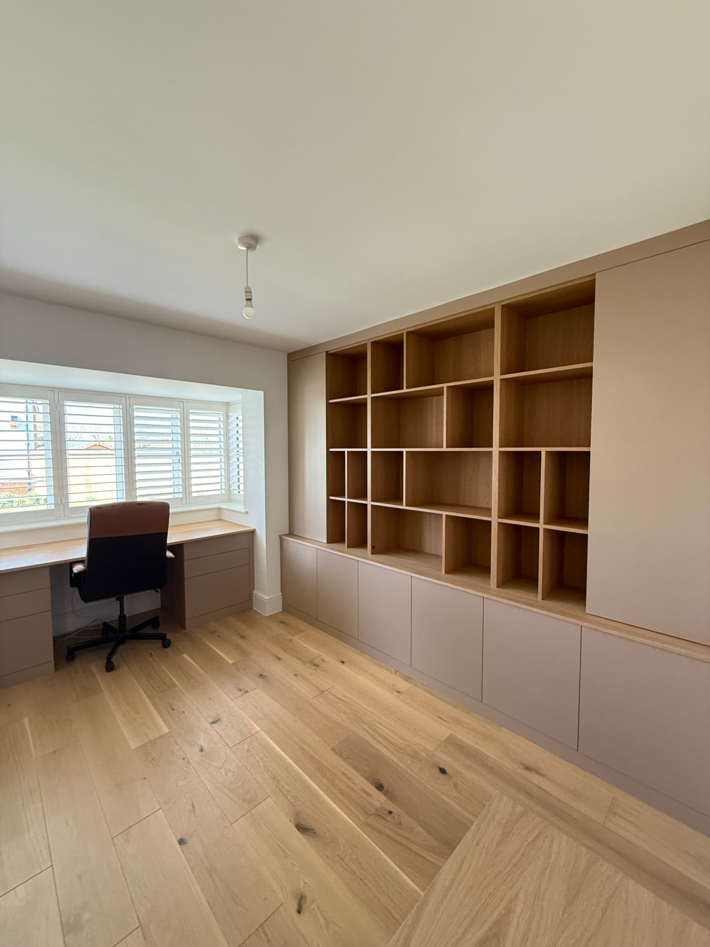 Bespoke home office with a fitted desk, drawer units and open oak shelving above painted cupboards