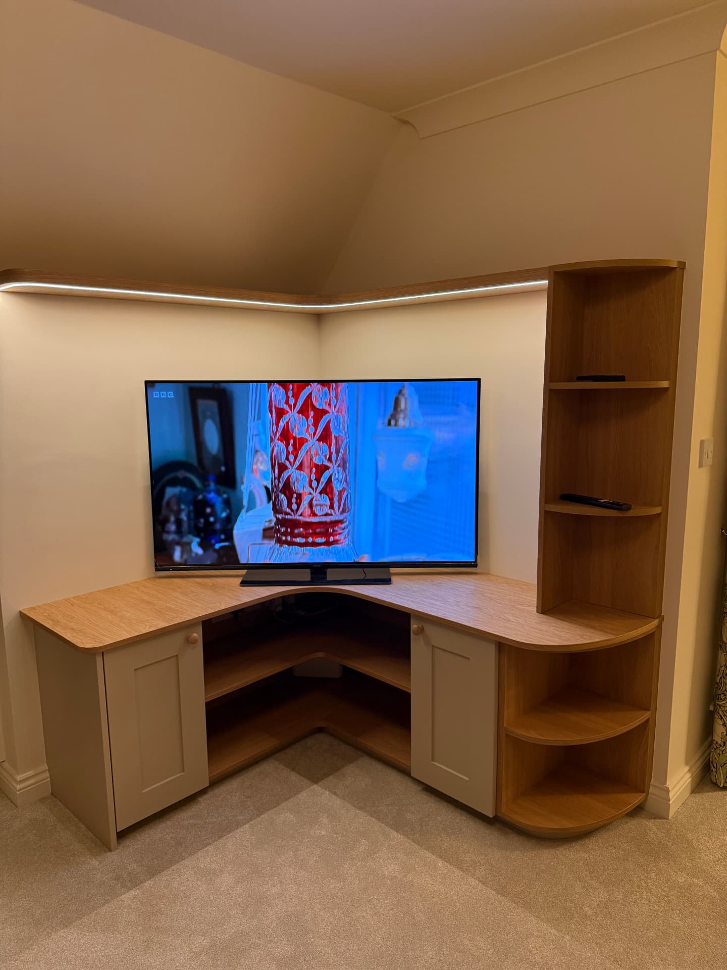 Curved corner TV unit in oak with painted shaker cupboards and open display shelving